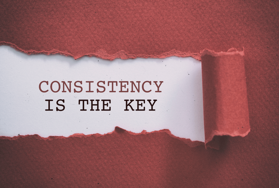 A paper that's being ripped away, displaying "Consistency is Key" underneath it